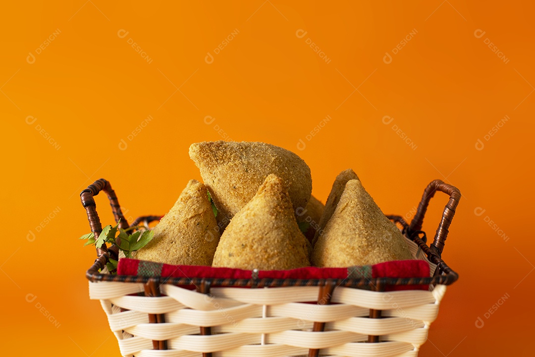 Cesta com deliciosas coxinhas de frango em fundo laranja