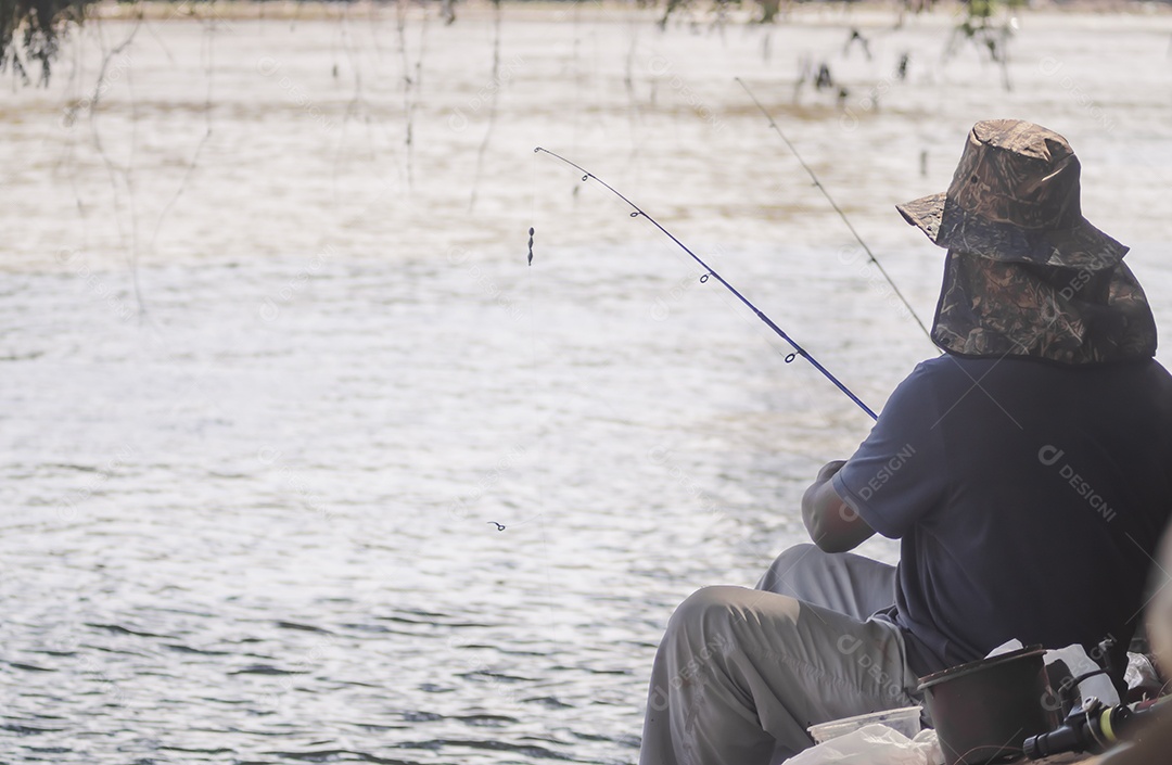 Homem pescando em um rio, o homem está de costas e não consegue ver o rosto, conceito de pesca.