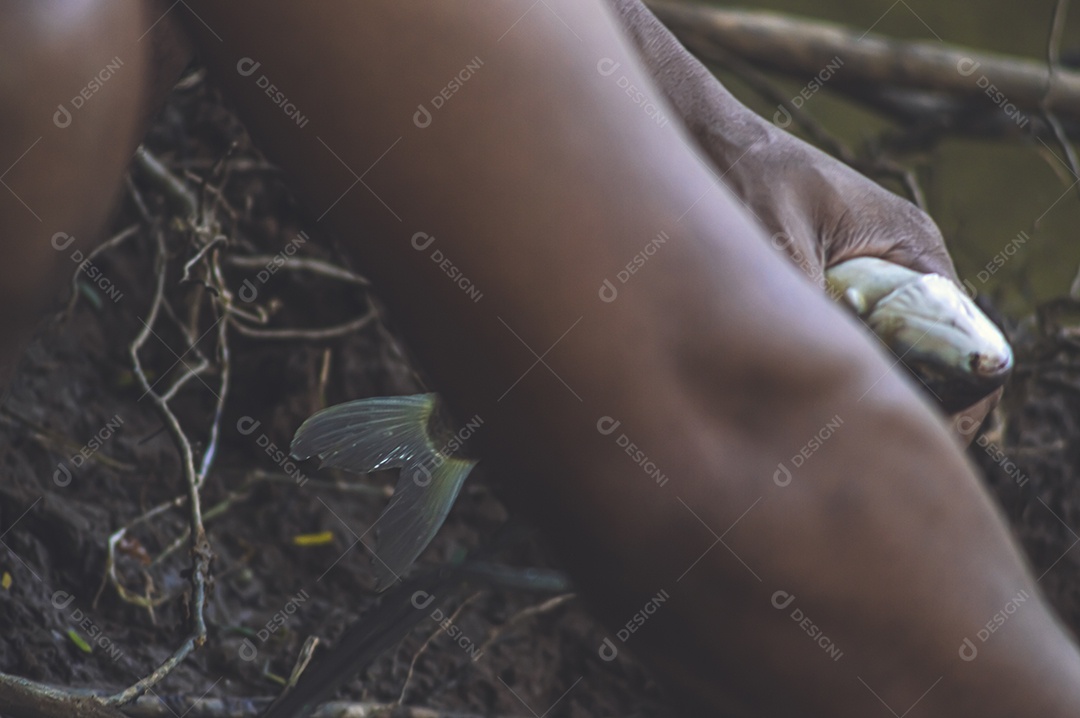 Homem tirando o anzol da boca de um peixe que acabou de pescar, conceito de pesca.