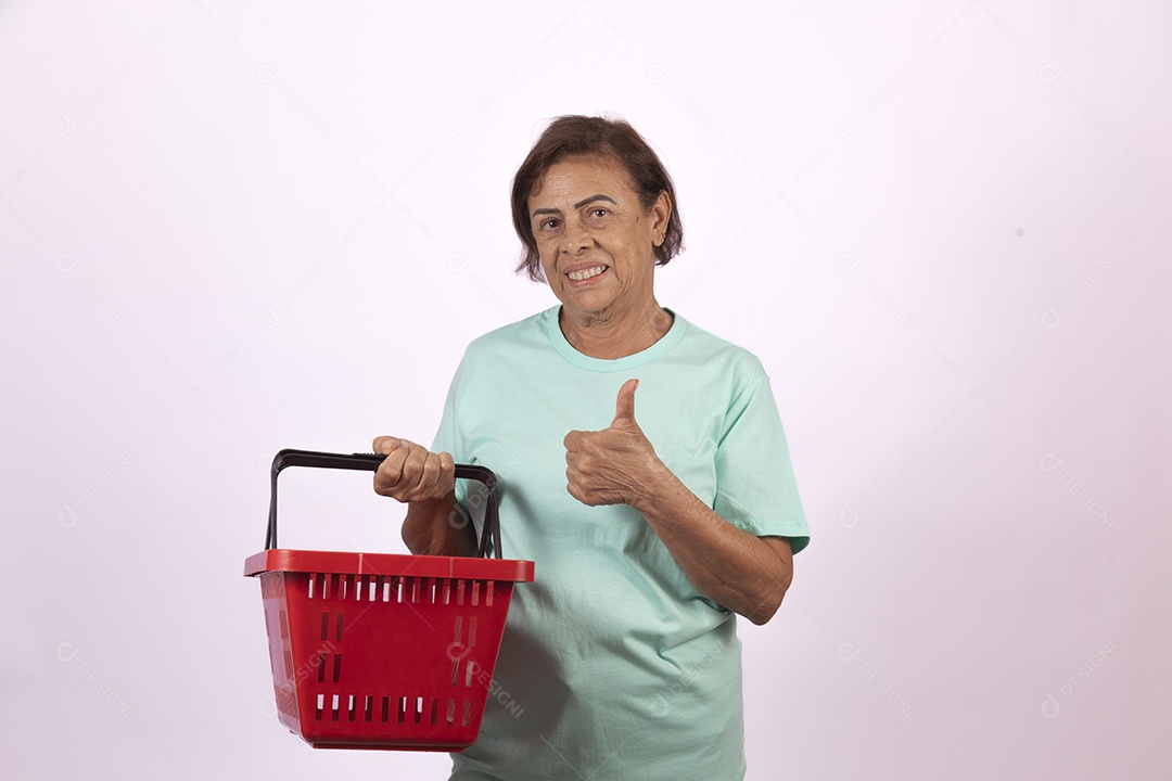 Mulher idosa morena segurando cesta de supermercado sobre fundo isolado