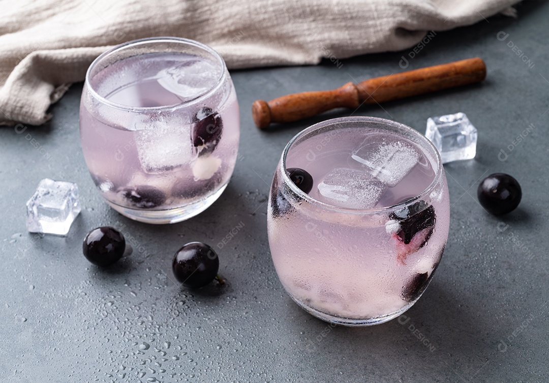Caipirinha de jabuticaba brasileira em copos com gelo e frutas sobre fundo de pedra.