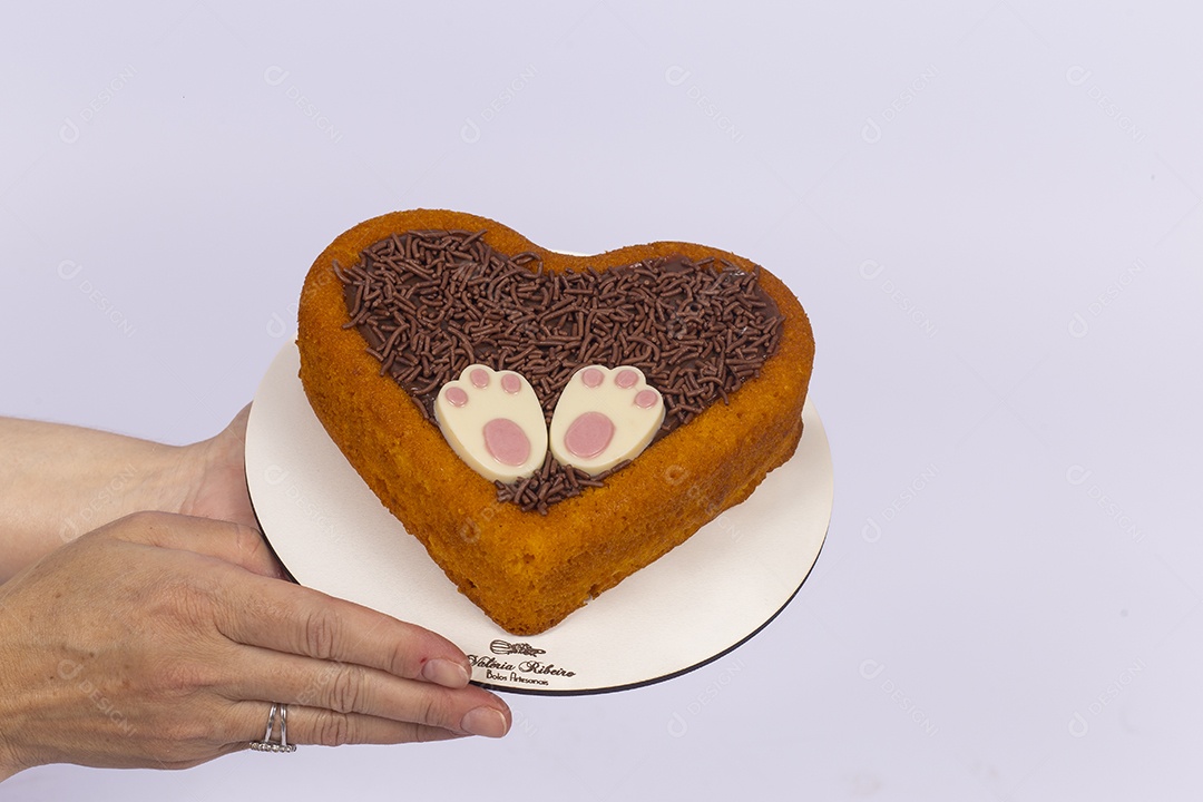 Mãos de pessoa segurando ovos de páscoa sobre uma prato branco