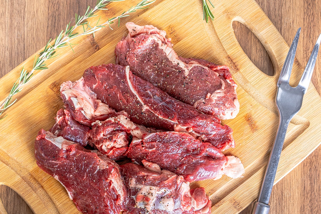 Bife do lombo cru cortado em bifes em uma placa de madeira