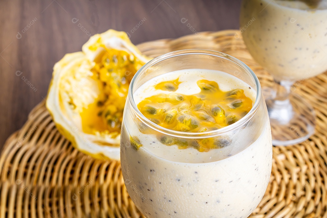 Mousse de maracujá em taça de vidro, com maracujá ao fundo