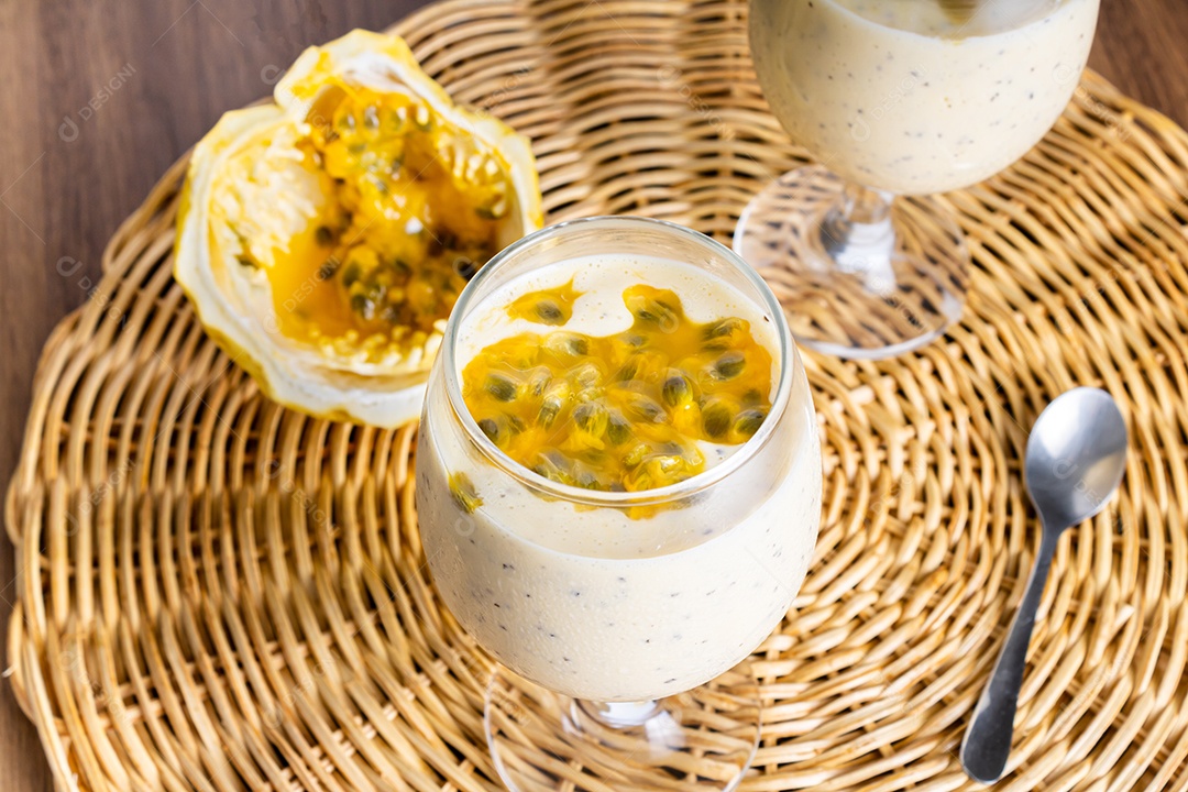 Mousse de maracujá em taça de vidro, com maracujá ao fundo