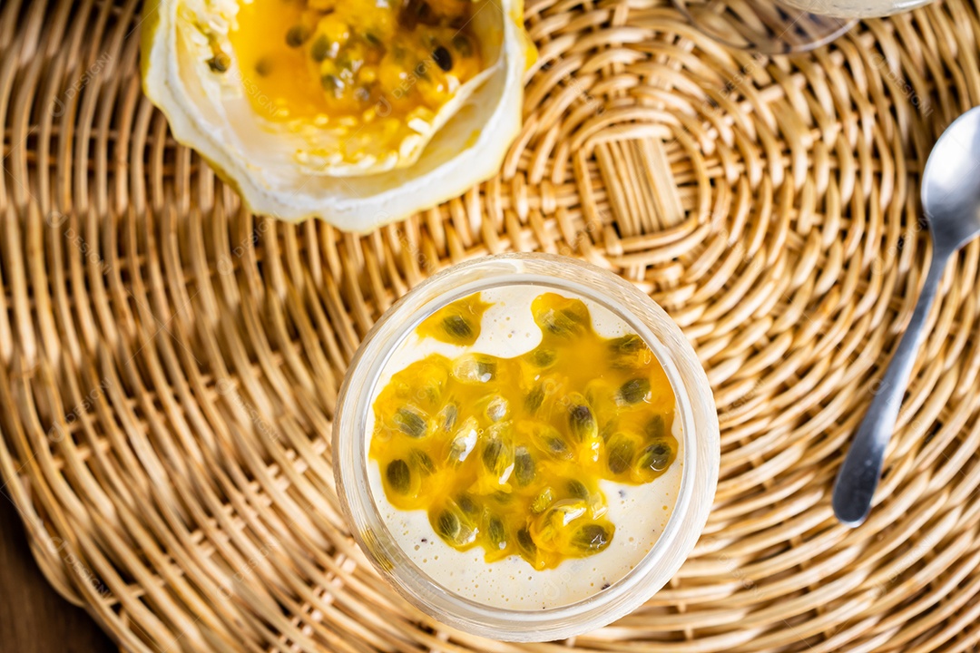 Mousse de maracujá em taça de vidro, com maracujá ao fundo