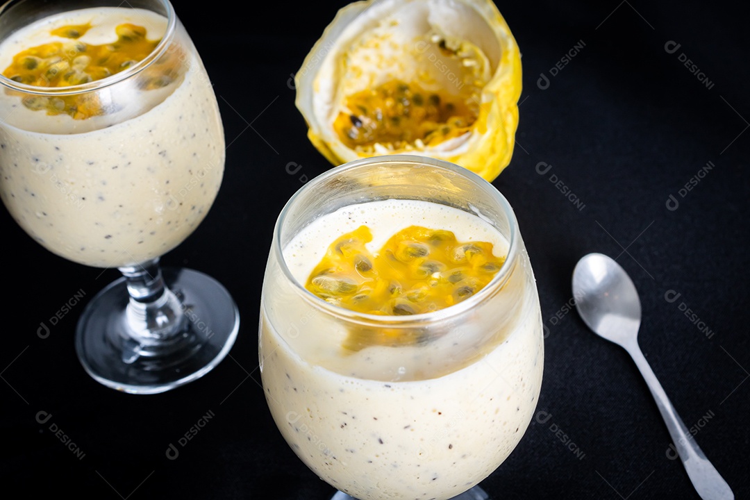 Mousse de maracujá em taça de vidro, com maracujá ao fundo