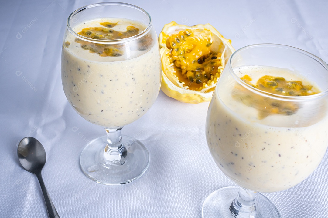 Mousse de maracujá em taça de vidro, com maracujá ao fundo