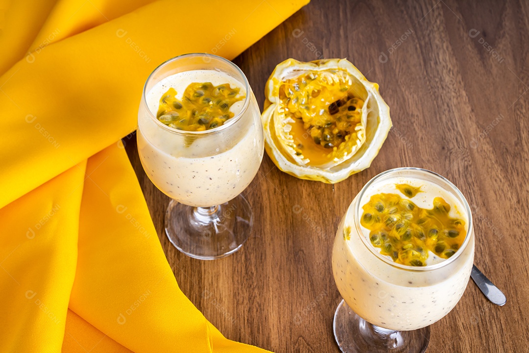 Mousse de maracujá em taça de vidro, com maracujá ao fundo
