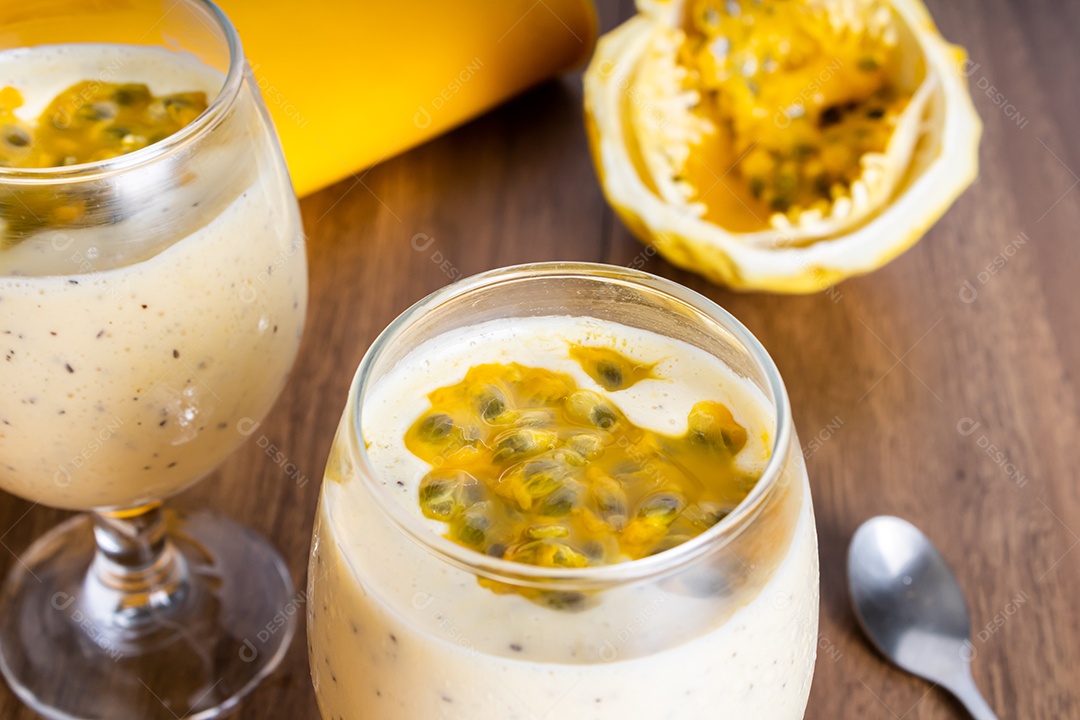 Mousse de maracujá em taça de vidro, com maracujá ao fundo