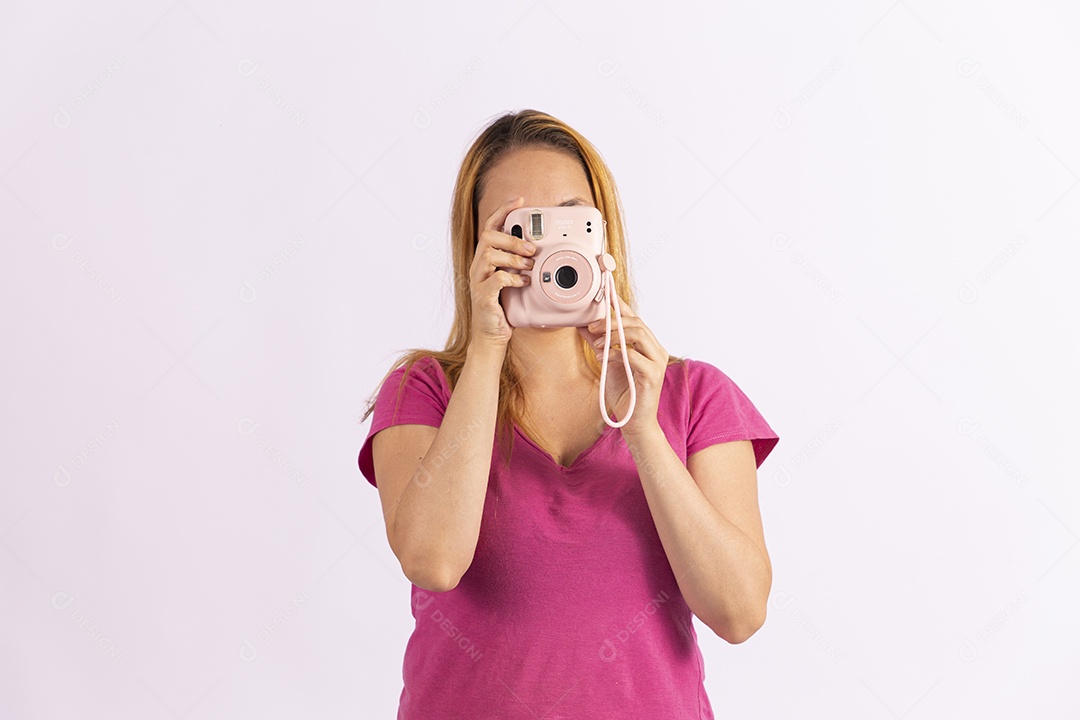 Linda mulher jovem segurando câmera fotográfica sobre fundo isolado