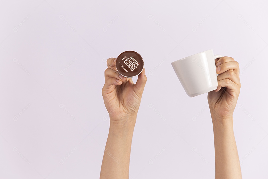 Mãos de pessoa segurando xícara e capsula de café