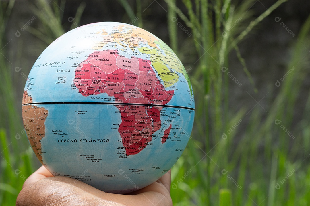 Mão segurando um globo terrestre com fundo verde