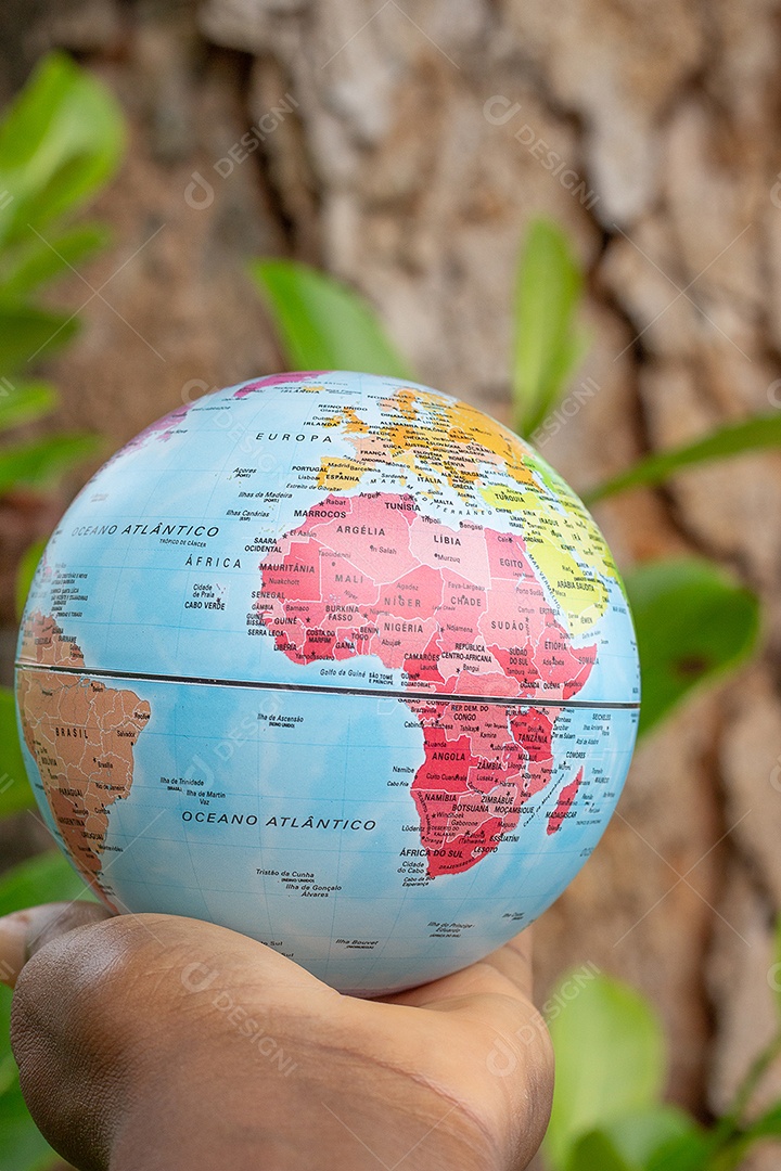 Mão segurando um globo terrestre com fundo verde