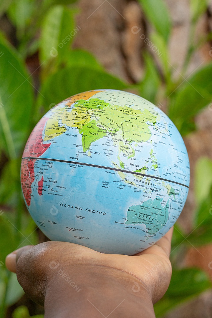 Mão segurando um globo terrestre com fundo de textura de madeira
