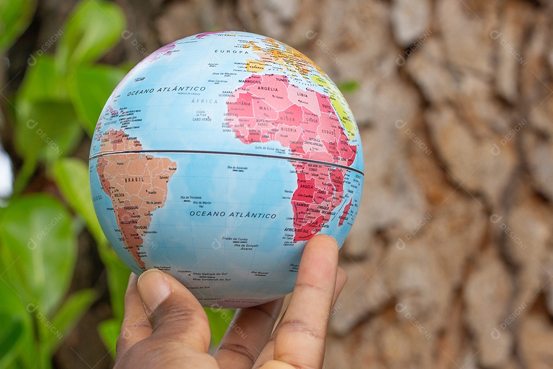 Mão segurando um globo terrestre com fundo de textura de madeira