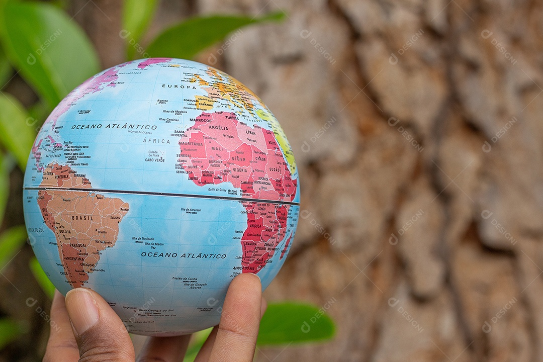 Mão segurando um globo terrestre com fundo de textura de madeira