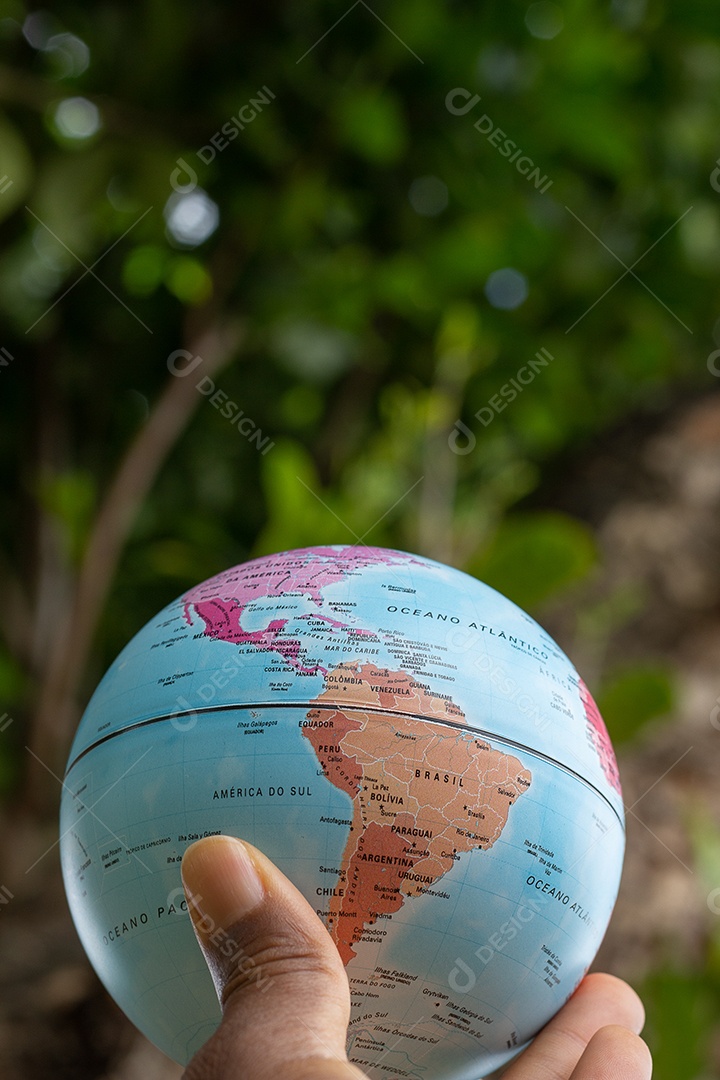 Mão segurando um globo terrestre com fundo de textura verde
