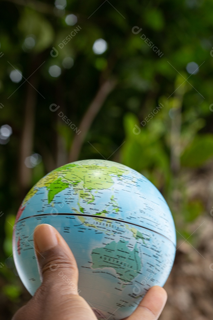 Mão segurando um globo terrestre com fundo de textura verde