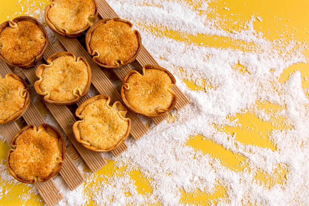 Doce de coco (cocadinha) e coco ralado em fundo amarelo