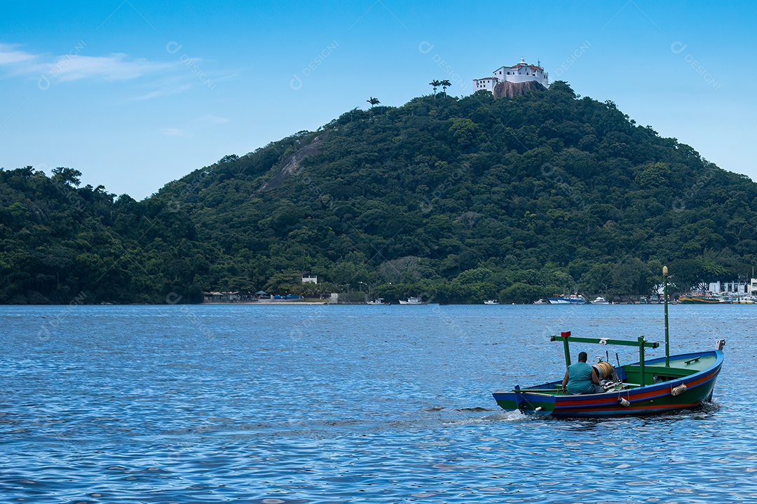 Convento da Penha ao fundo e um pescador conduzindo um barco em primeiro plano.