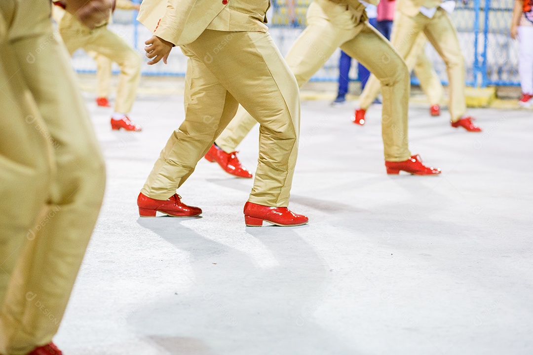 Sambista com calças cor de areia e sapatos vermelhos se apresentando no Rio de Janeiro, Brasil.