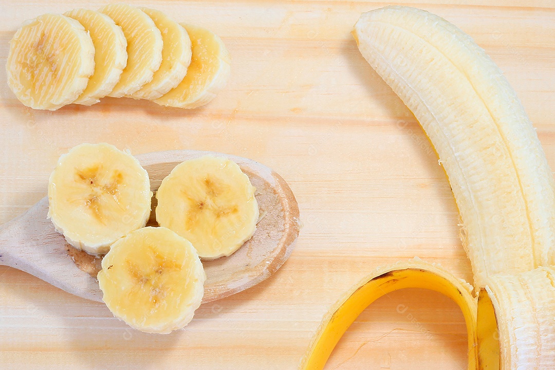 Fatias de banana na colher sobre fundo de madeira. Lanche natural saudável.