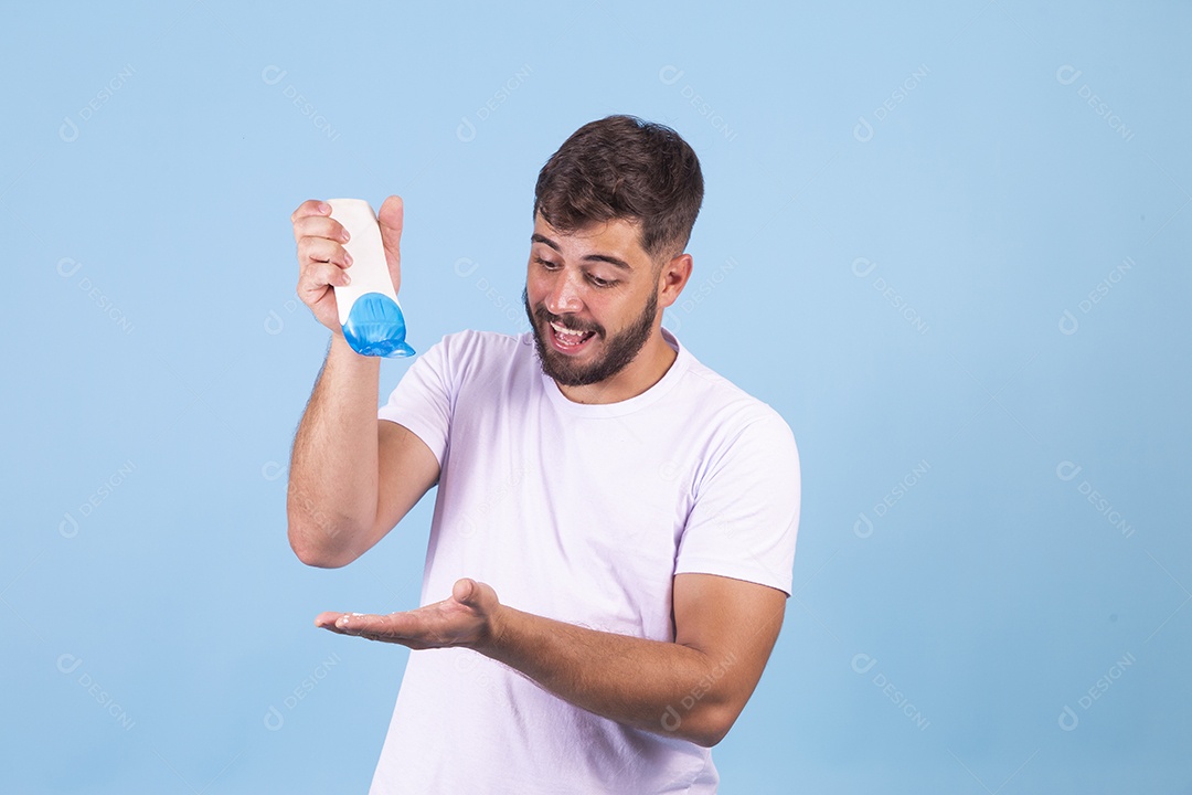 Homem jovem segurando frasco de produto para o rosto sobre fundo isolado