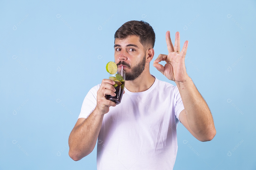 Homem jovem segurando bebida curtindo férias sobre fundo isolado