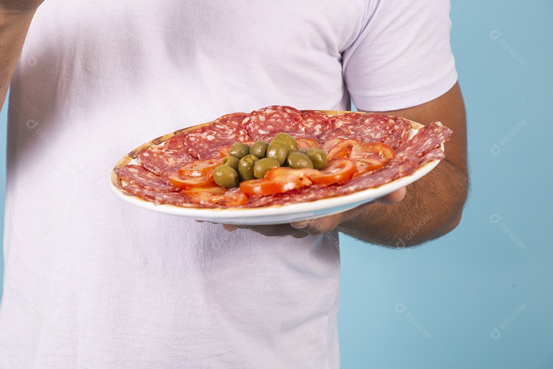 Mãos segurando prato de salame com azeitonas sobre fundo isolado