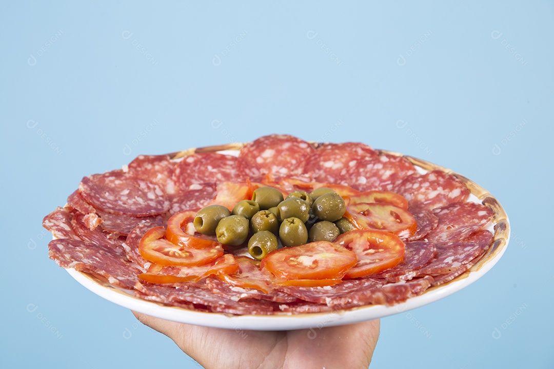 Mãos segurando prato de salame com azeitonas sobre fundo isolado