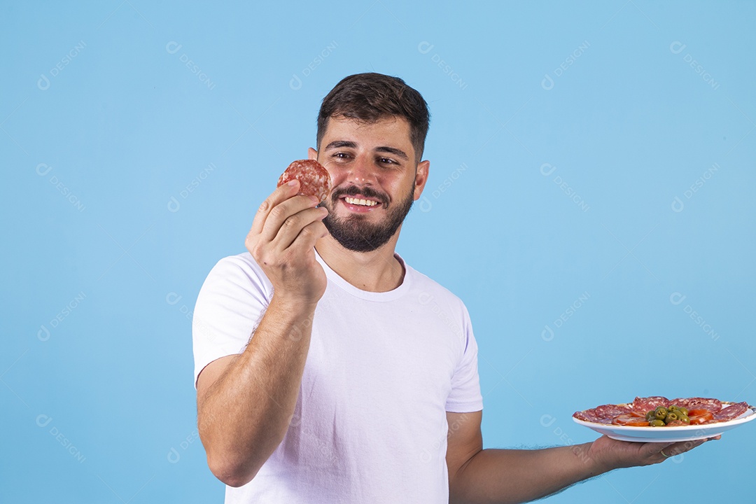 Homem jovem segurando fatia de salame sobre fundo isolado
