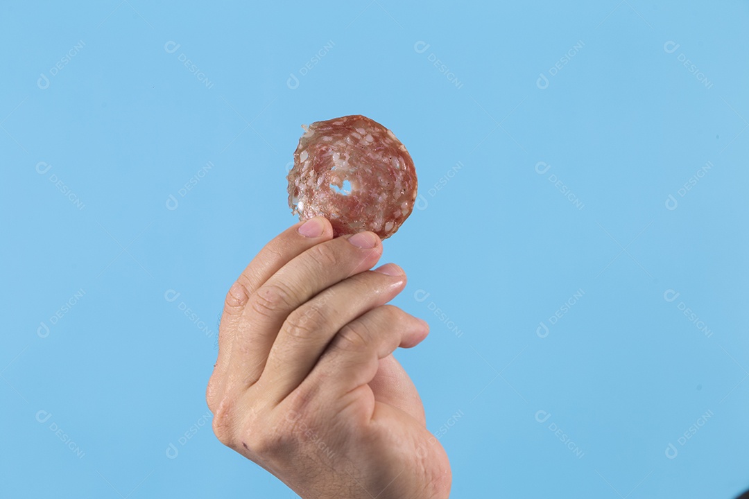 Mãos pessoa jovem segurando fatia de salame sobre fundo isolado