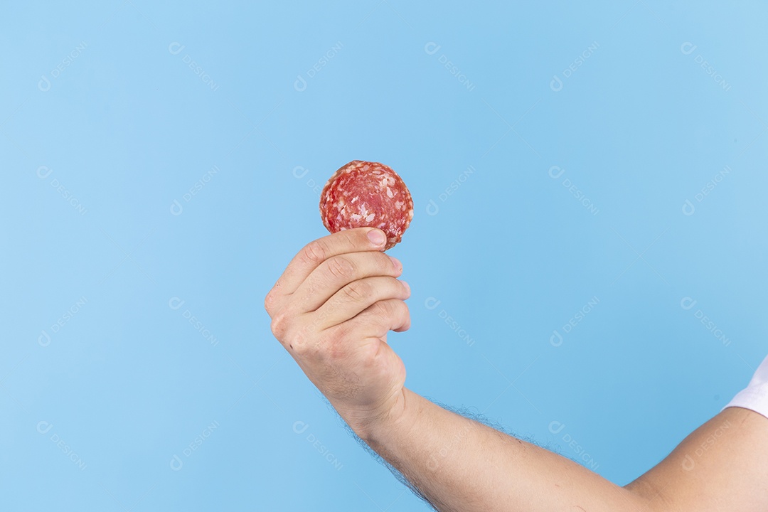 Homem jovem segurando fatia de salame sobre fundo isolado