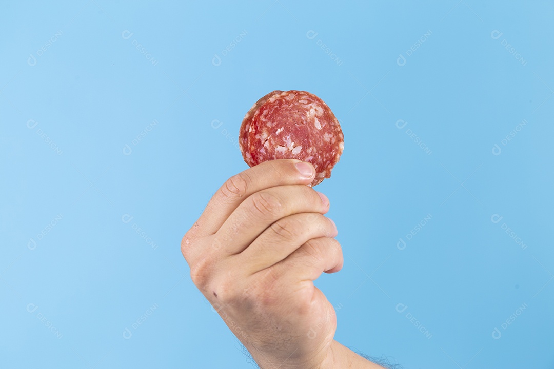 Homem jovem segurando fatia de salame sobre fundo isolado