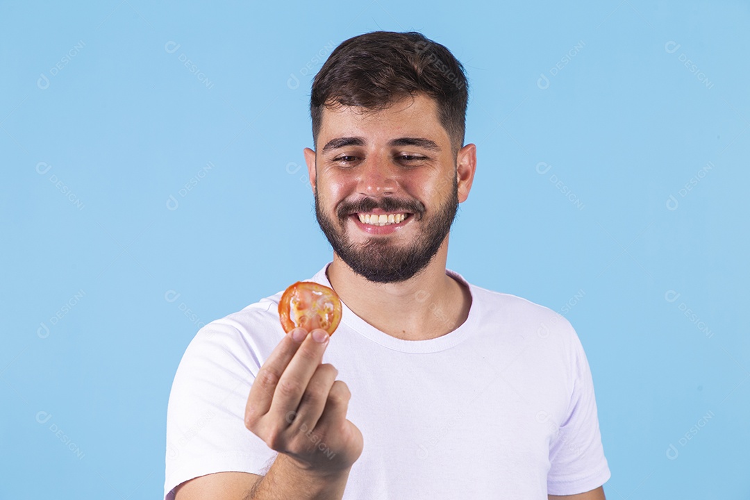 Homem jovem segurando fatia de tomate sobre fundo isolado