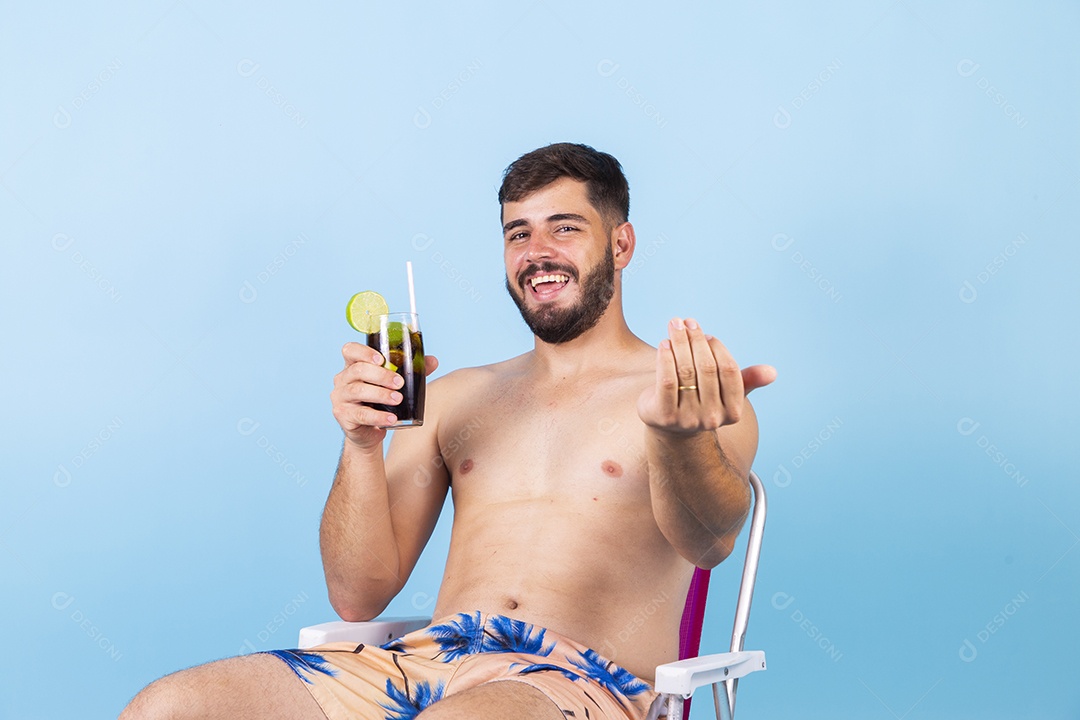Homem jovem segurando bebida curtindo férias sobre fundo isolado