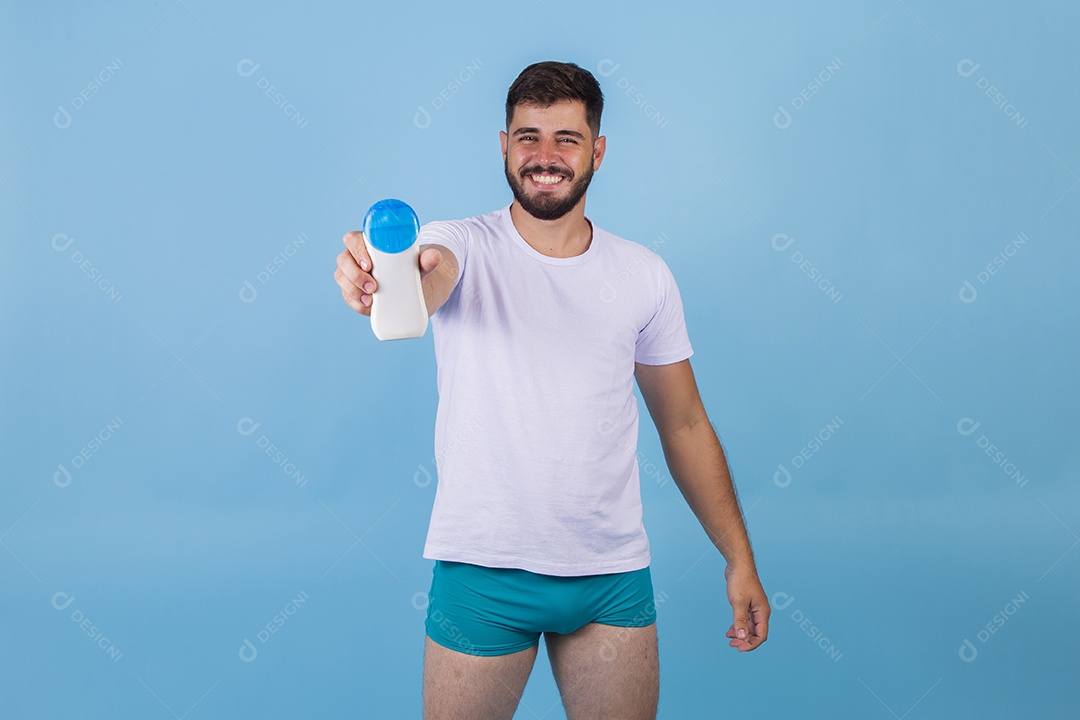 Homem jovem segurando frasco de produto para o rosto sobre fundo isolado