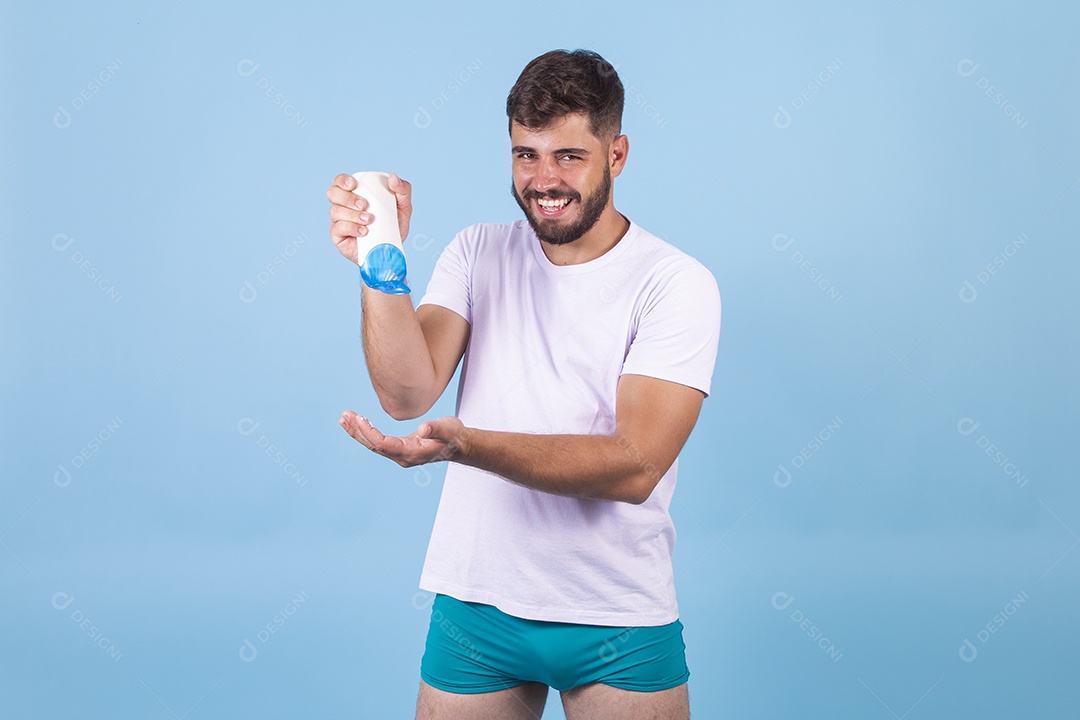 Homem jovem usando produto para o rosto sobre fundo isolado