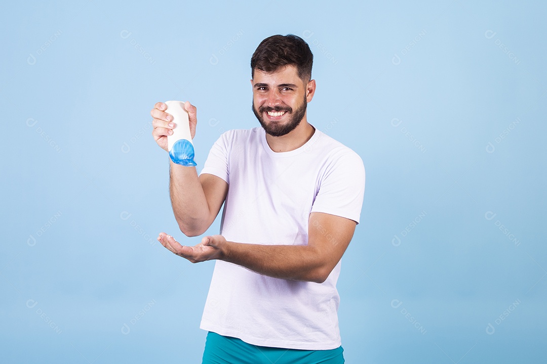 Homem jovem usando produto para o rosto sobre fundo isolado