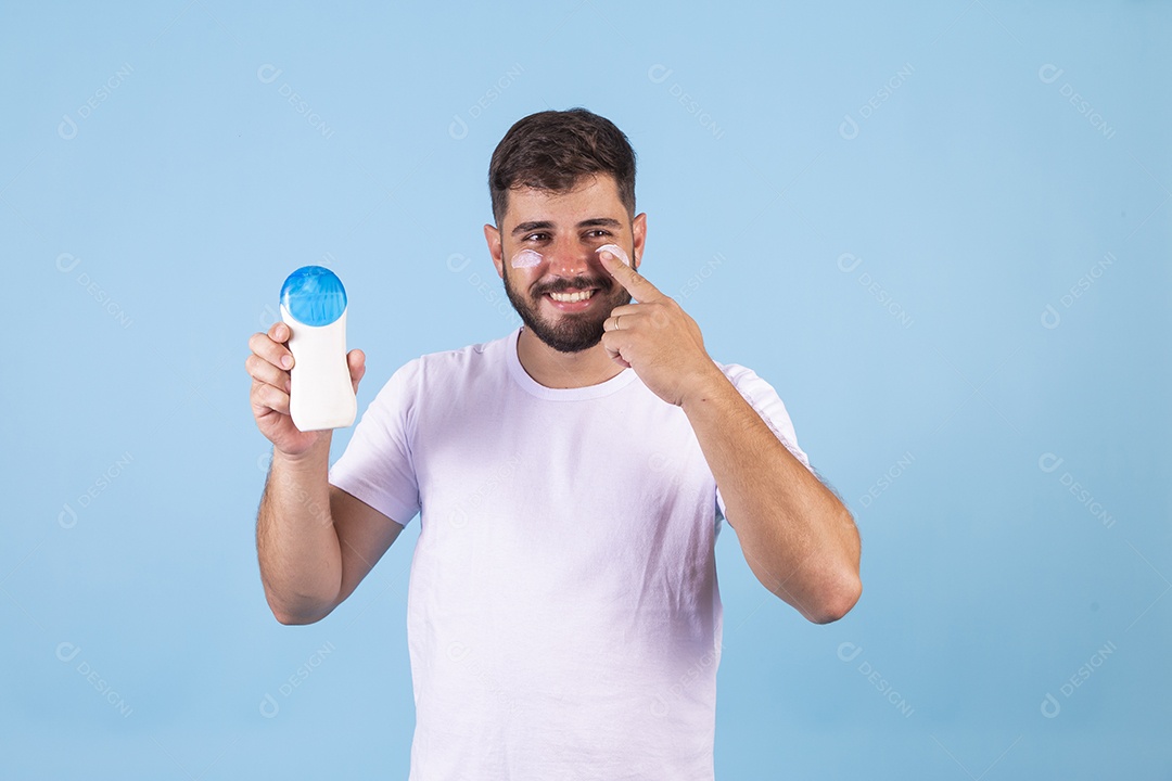 Homem jovem usando produto para o rosto sobre fundo isolado