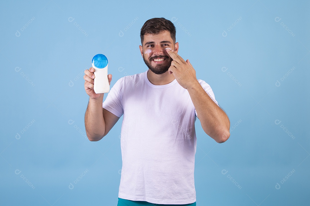 Homem jovem usando produto para o rosto sobre fundo isolado