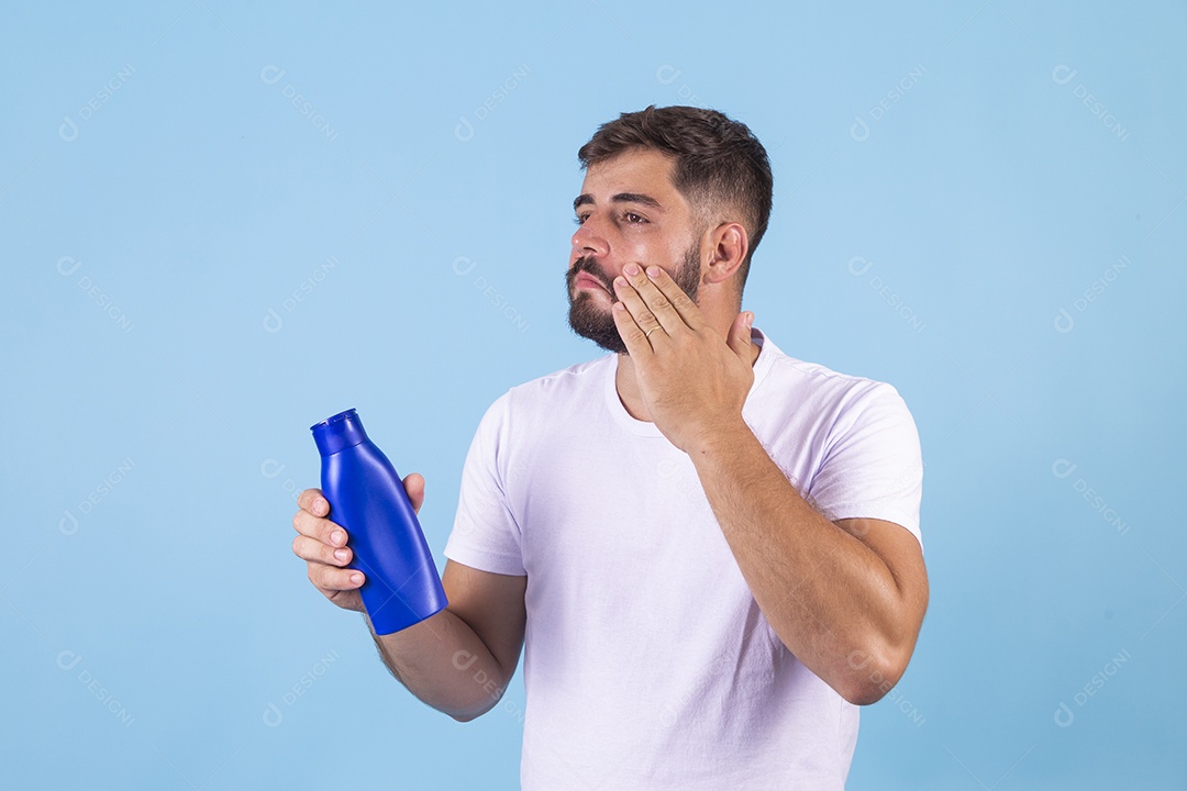 Homem jovem segurando frasco de produto para o rosto sobre fundo isolado