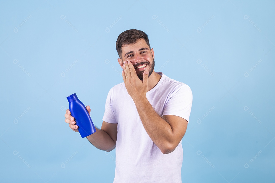 Homem jovem segurando frasco de produto para o rosto sobre fundo isolado