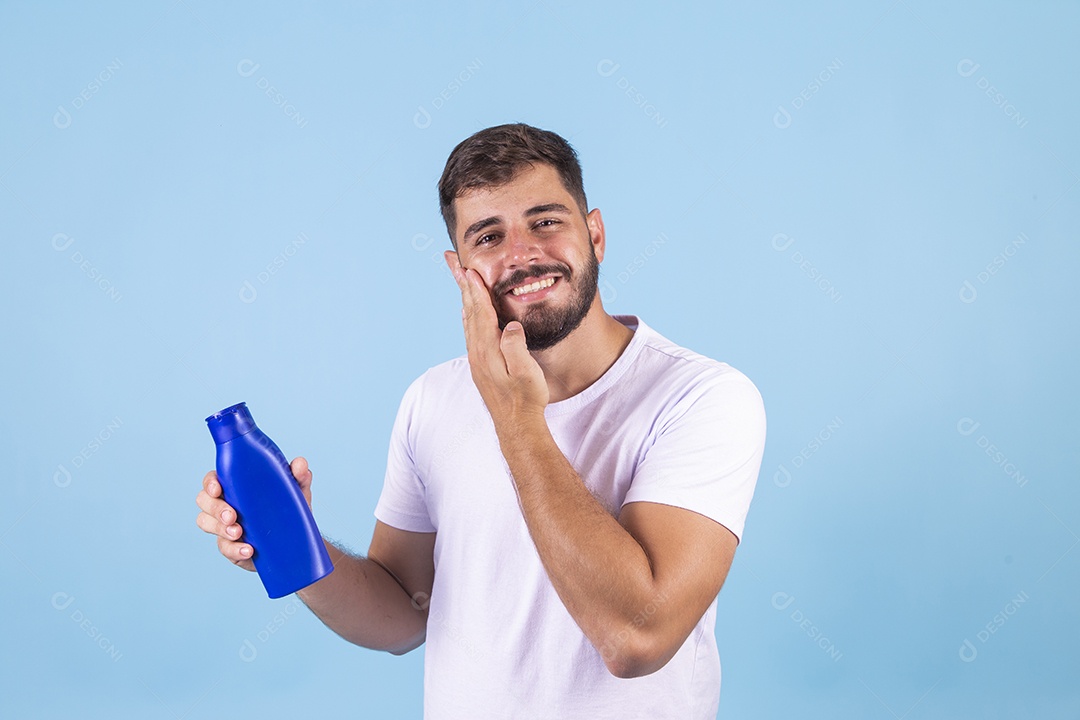 Homem jovem segurando frasco de produto para o rosto sobre fundo isolado