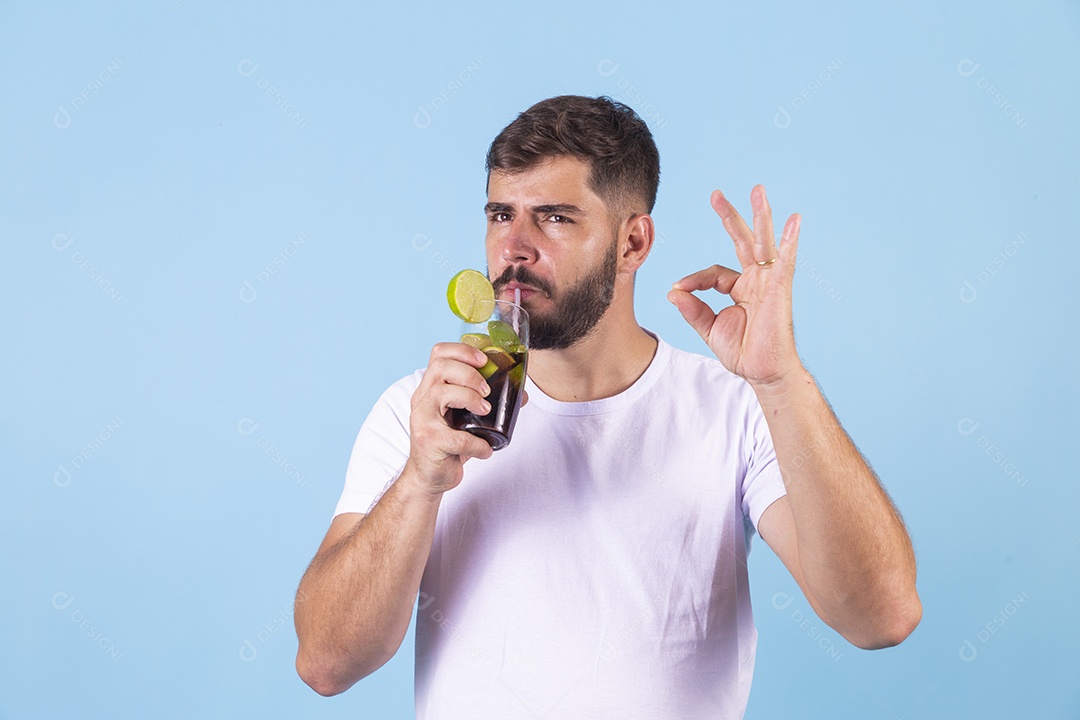 Homem jovem bebendo bebida sobre fundo isolado