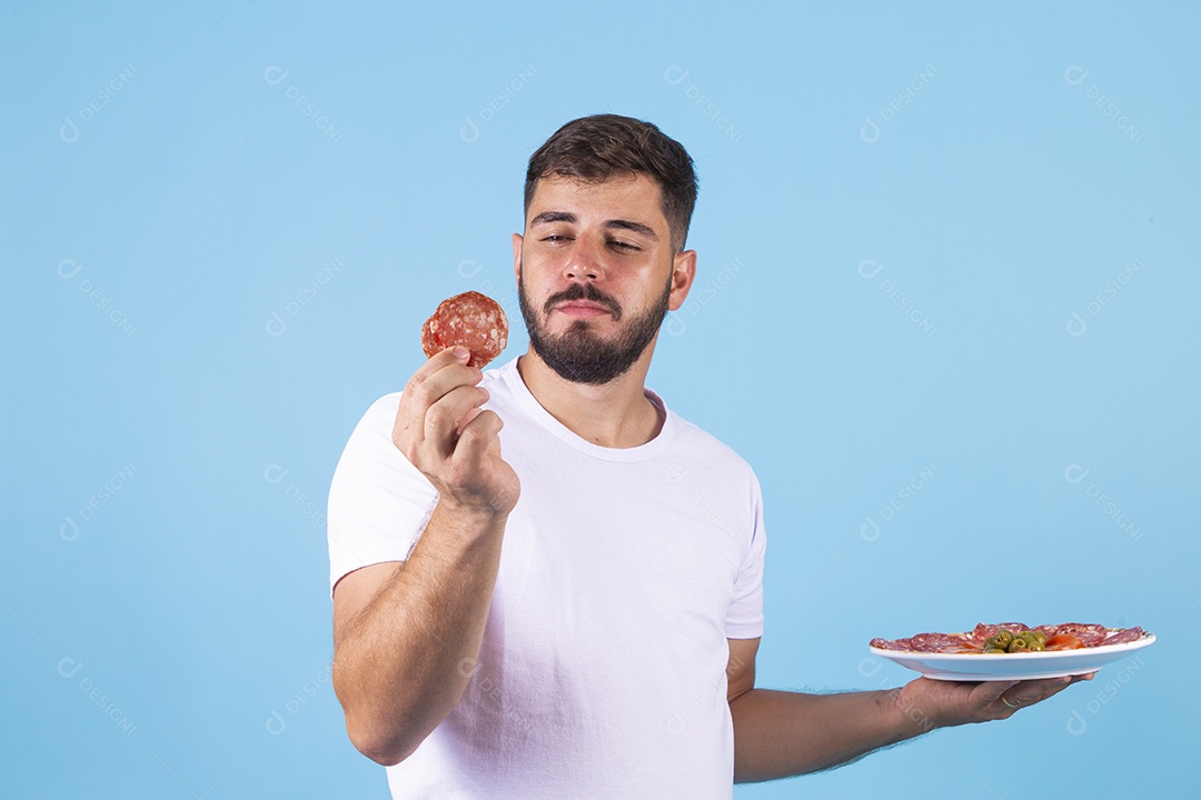 Homem jovem segurando prato de salame sobre fundo isolado