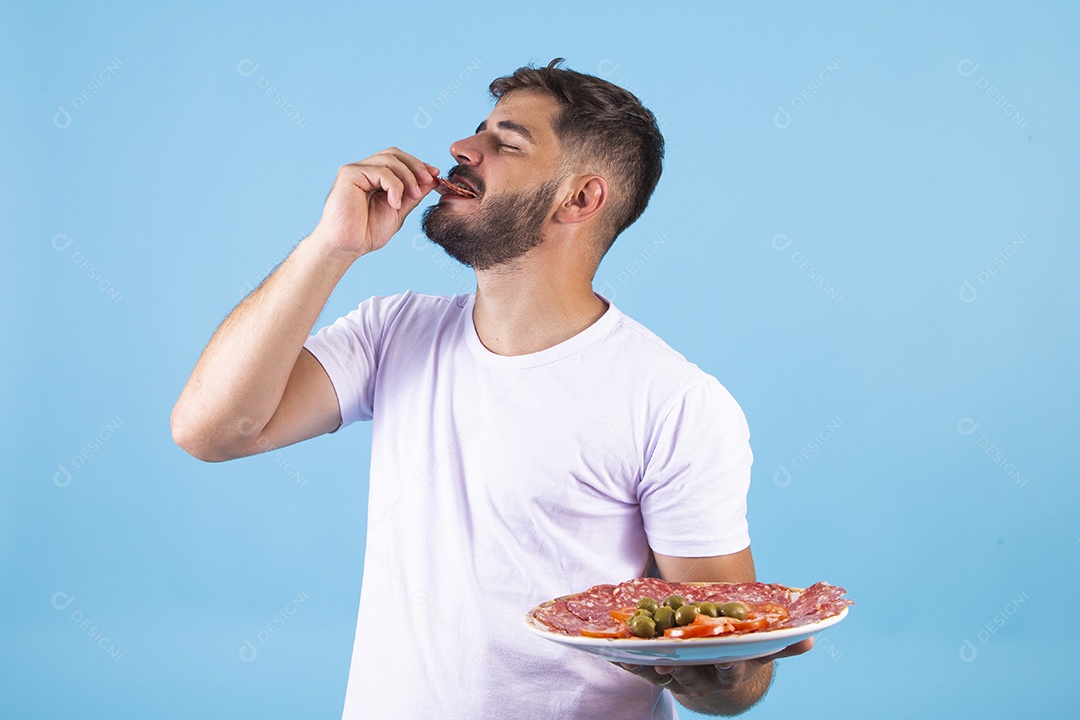 Homem jovem se alimentando com salame sobre fundo isolado