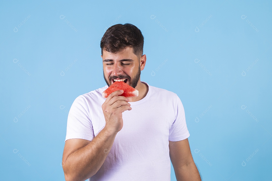 Homem jovem se alimentando com melancia sobre fundo isolado