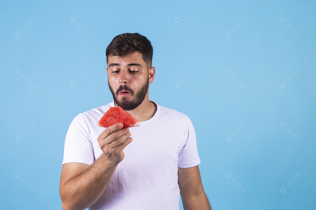Homem jovem se alimentando com melancia sobre fundo isolado